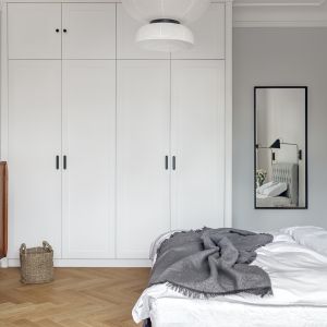 Szara sypialnia z pikowanym zagłówkiem i białą szafą. Projekt wnętrza: pracownia Luumo. Zdjęcia: Tom Kurek