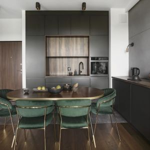Czarna kuchnia z jadalnią z ciemnozielonymi krzesłami i brązowym stołem. Projekt wnętrza Decoroom. Fot. Fotografka