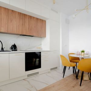 Drewno i kolor biały w małym salonie z kuchnią. Projekt wnętrza i zdjęcia: KODO Projekty i Realizacje Wnętrz