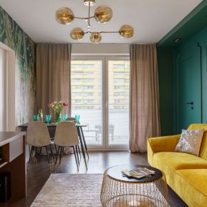  Zielone ściany, żółta sofa i brązowe meble w małym salonie z kuchnią. Projekt wnętrza: Donata Gadalska. Zdjęcia: Jacek Fabiszewski