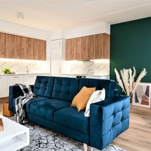Niebieska kanapa w salonie połączonym z kuchnią. Projekt wnętrza i zdjęcie: KODO Projekty i Realizacje Wnętrz