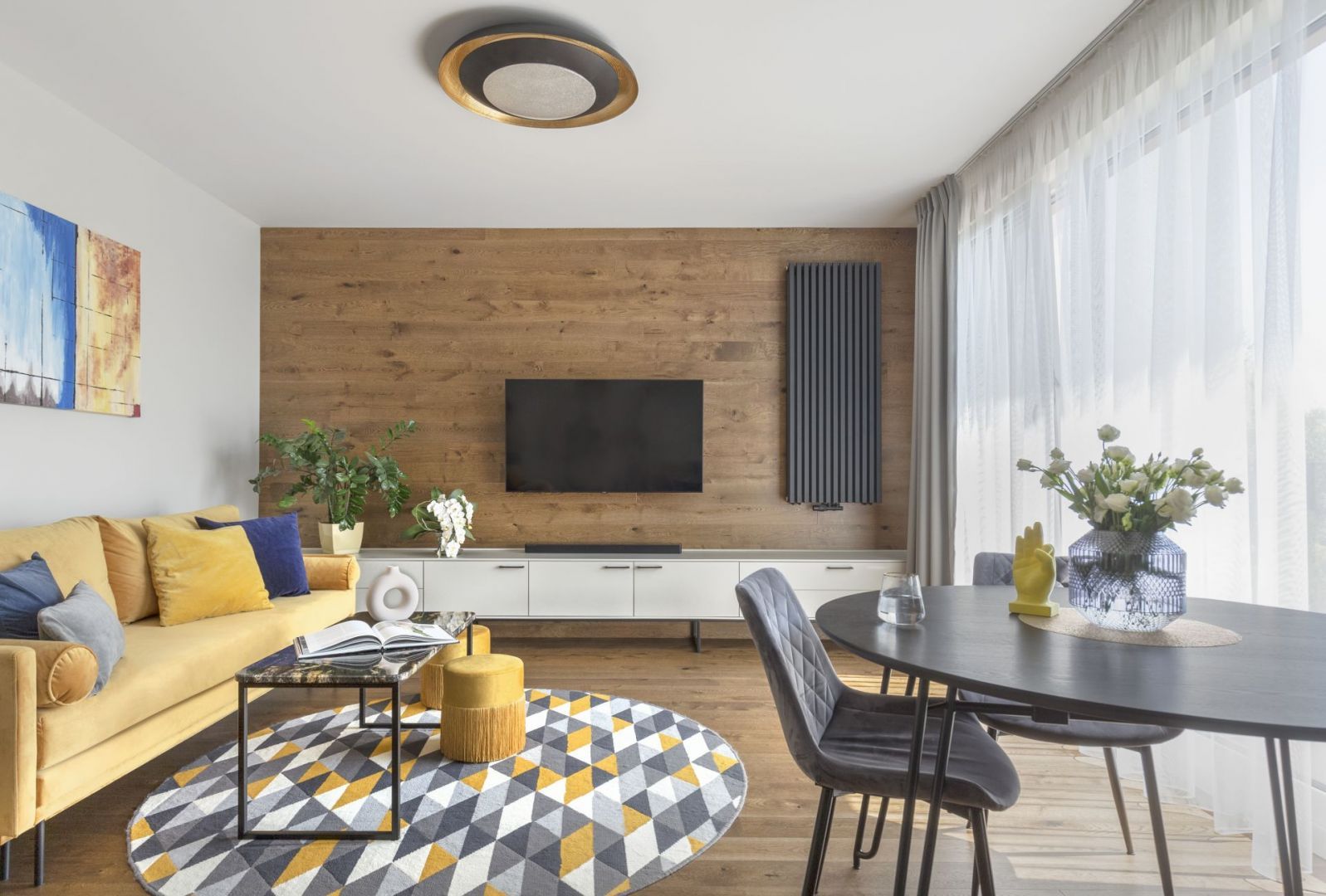 Drewno na ścianie i żółta kanapa w salonie w bloku. Projekt wnętrza: Ewa Dziurska, Decoroom. Zdjęcia i stylizacja: Marta Behling, Pion Poziom