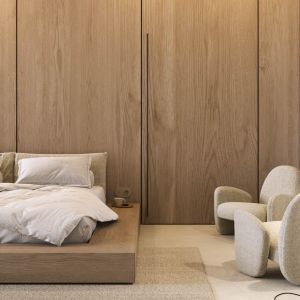 W sypialni dominują ciepłe, jasne barwy i drewno, z którego wykonano łóżko oraz ścianę za jego wezgłowiem, połączoną z drzwiami do ukrytej garderoby. Projekt wnętrza: Paulina Boruch, Scena Interior Design