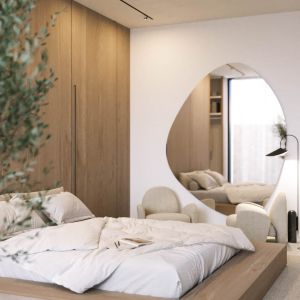 W sypialni doskonale łączą się ze sobą gładkie powierzchnie drewna, kamienia czy tafli dużego lustra o organicznych kształtach. Projekt wnętrza: Paulina Boruch, Scena Interior Design