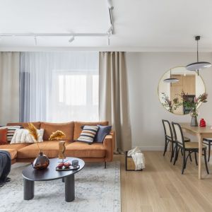 Ruda sofa w salonie, naturalne materiały w kuchni z jadalnią. Projekt wnętrza: WZ Studio. Fot. PionPoziom