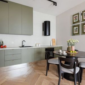 Sztukaterie na ścianie i różowa sofa w salonie, zielone meble w kuchni. Projekt wnętrza: Decoroom. Fot. Marek Koptyński