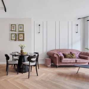 Sztukaterie na ścianie i różowa sofa w salonie, zielone meble w kuchni. Projekt wnętrza: Decoroom. Fot. Marek Koptyński