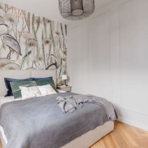 Tapeta z oryginalnym wzorem na ścianie za łóżkiem w małej sypialni. Projekt wnętrza: Decoroom. Fot. Marek Koptyński