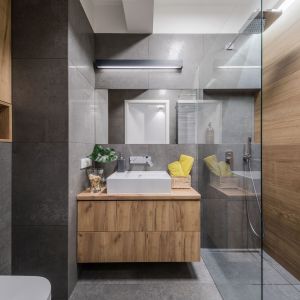 Nowoczesna łazienka z prysznicem, w której zastosowano dwa rodzaje płytek – ciemne z motywem betonu i drewna. Projekt wnętrza i zdjęcie: KODO Projekty i Realizacje Wnętrz