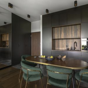 Pomysł na jadalnię: ciemny drewniany stół i tapicerowane krzesła w kolorze ciemnej zieleni. Projekt wnętrza Decoroom. Fot. Fotografka