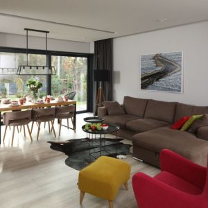 Brązowa kanapa i różowy fotel w nowoczesnym salonie. Projekt wnętrza: Laura Sulzik. Fot. Bartosz Jarosz