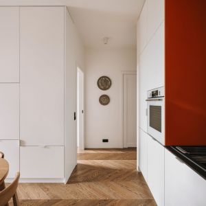 Mieszkanie urządzone jest w bieli i drewnie, z dodatkiem ceglastej czerwieni i czerni. Projekt wnętrza: WAM studio projektowe. Zdjęcia: Migdał Studio