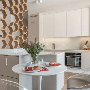 Salon z kuchnią w 45-metrowym mieszkaniu: biel i przytulny beż. Projekt wnętrza i zdjęcie: KODO Projekty i Realizacje Wnętrz