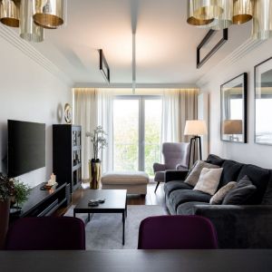 Salon dla rodziny: ciemne meble, obrazy na ścianie za kanapą. Projekt wnętrza: Dekorian Home x Architaste. Fot. Dominika Wilk