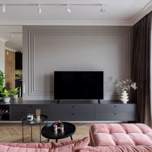 Salon z różową sofą i sztukaterią na ścianie za telewizorem. Projekt wnętrza latreDesign. Fot. Bernadetta Kuczyńska
