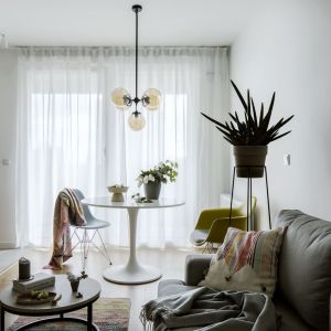 36-metrowe mieszkanie. Szara kanapa i grafiki na ścianie w małym salonie. Projekt wnętrza: Poco Design. Fot. Yassen Hristov
