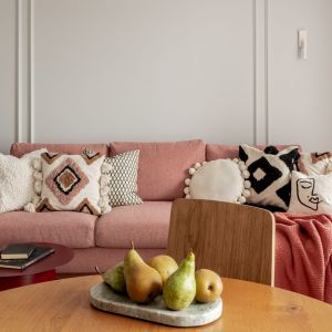 Różowa sofa na tle ściany wykończonej sztukateriami. Projekt: One Design. Fot. Aleksandra Dermont