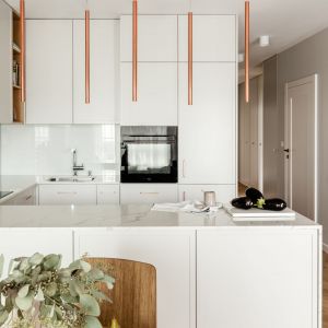 Białe fronty kuchenne i miedziane lampy w nowoczesnym stylu. Projekt: One Design. Fot. Aleksandra Dermont