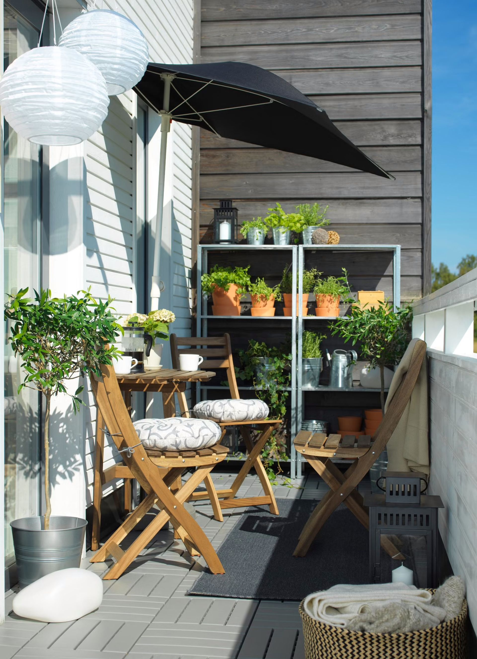 Pomysł na mały balkon w bloku. Pionowy regał na rośliny i parasol ogrodowy na balkon. Fot. IKEA