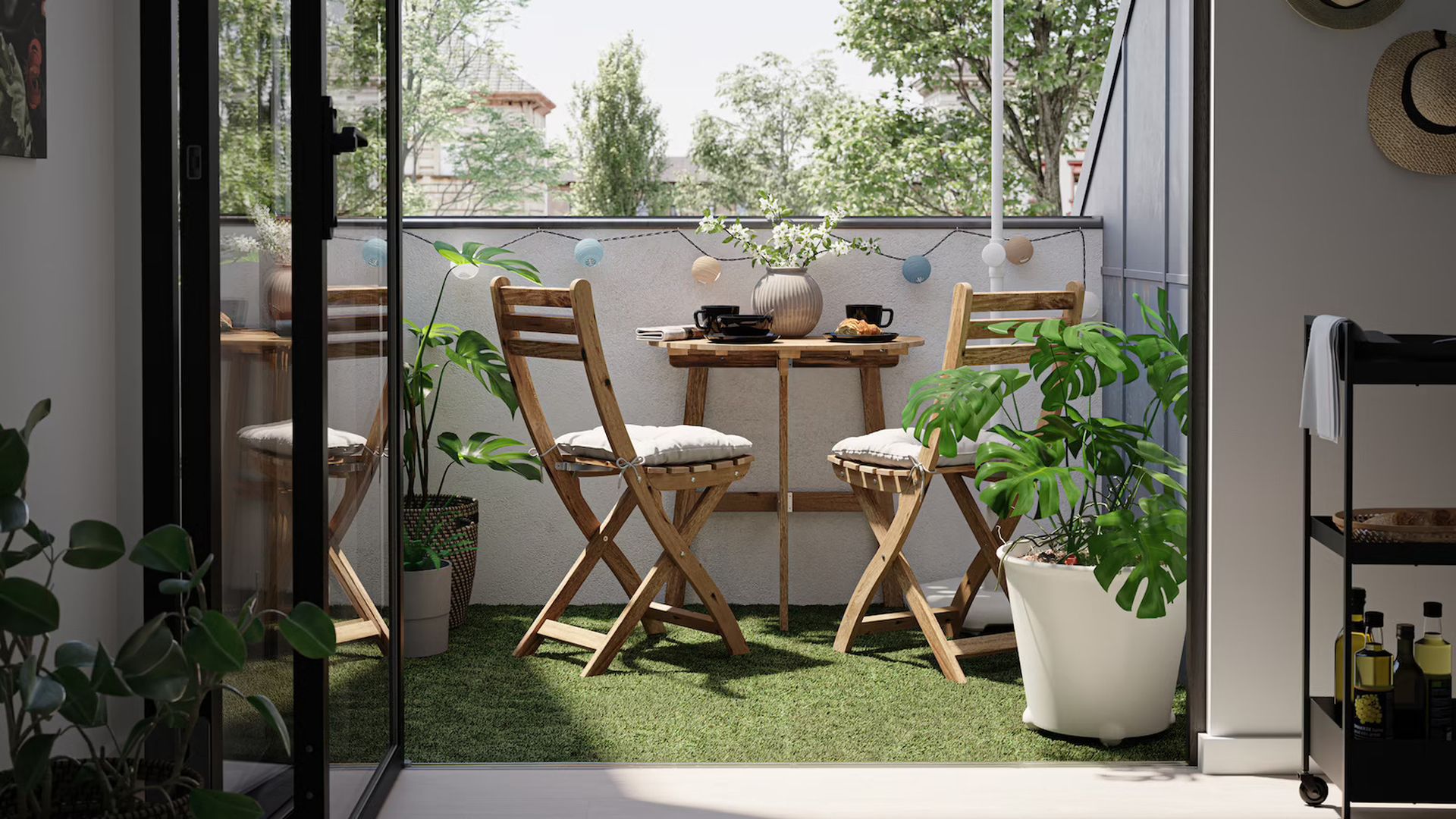 Mały balkon w bloku z drewnianymi krzesłami i sztuczną trawą. Fot. IKEA