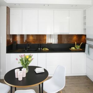 Dwupokojowe mieszkanie: białe meble i czarny blat w małej kuchni. Projekt wnętrza: Małgorzata Galewska. Fot. Bartosz Jarosz