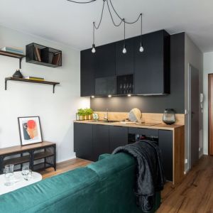 Mieszkanie o powierzchni 26 m²: ciemne meble i drewno w małej kuchni. Projekt wnętrza i zdjęcie: KODO Projekty i Realizacje Wnętrz 