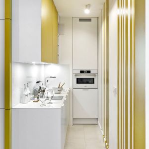 Biała kuchnia z musztardowymi frontami. 30-metrowe mieszkanie. Projekt wnętrza Katarzyna Rohde, pracownia Home&Style. Fot. Bernard Białorucki