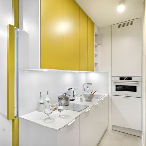 Biała kuchnia z musztardowymi frontami. 30-metrowe mieszkanie. Projekt wnętrza Katarzyna Rohde, pracownia Home&Style. Fot. Bernard Białorucki