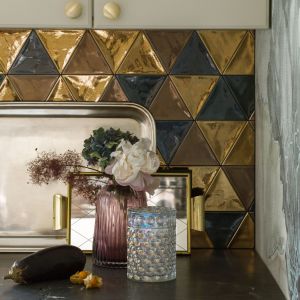 Ścianę nad blatem w kuchni zdobi trójkątna mozaika firmy Quintesenza, złożona z czarnych i złotych trójkątów. Projekt wnętrze: MM Architekci. Fot. Yassen Hristov. Stylizacja: Patrycja Rabińska