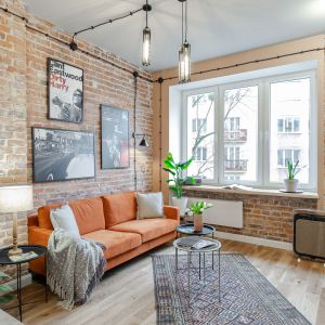 Pomarańczowa sofa i ściana z cegłą w salonie w kamienicy. Projekt wnętrza Latre Design. Fot. Bernadetta Kuczyńska