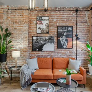 Pomarańczowa sofa i ściana z cegłą w salonie w kamienicy. Projekt wnętrza Latre Design. Fot. Bernadetta Kuczyńska