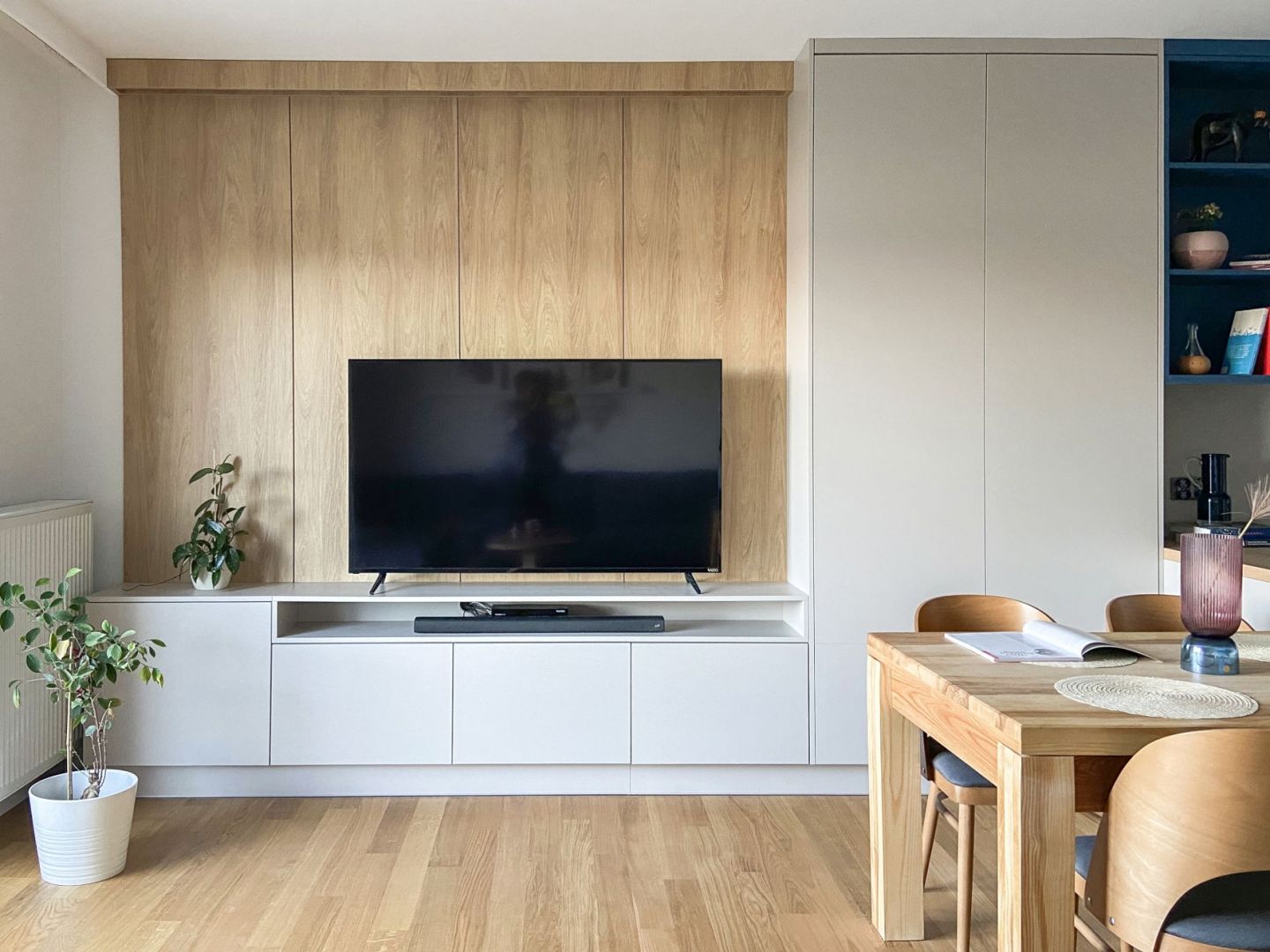 Ścianę za telewizorem w salonie zdobi jasne drewno. Projekt wnętrza: Adam Jankowski, Kamil Paszek, AMJ studio. Fot. AMJ studio