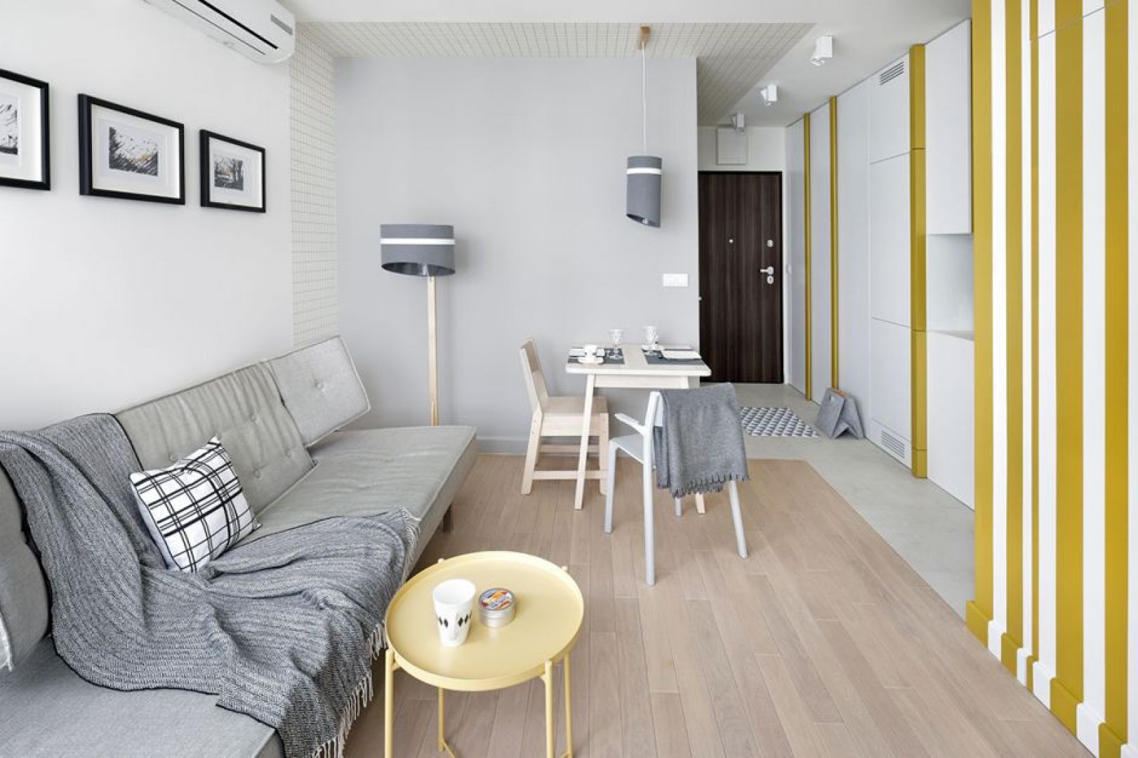 Szara kanapa i drewniana podłoga w małym salonie. Projekt wnętrza: Katarzyna Rohde, pracownia Home&Style. Fot. Bernard Białorucki