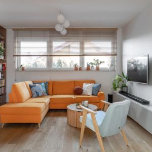 Białe ściany i pomarańczowa kanapa w małym salonie. Projekt wnętrza: Lekka Forma Pracownia Projektowa. Fot. Natalia Kaczmarek, Inkadr